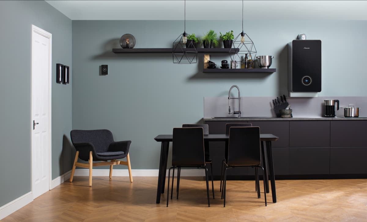 A kitchen with a black boiler, black table and black chairs.